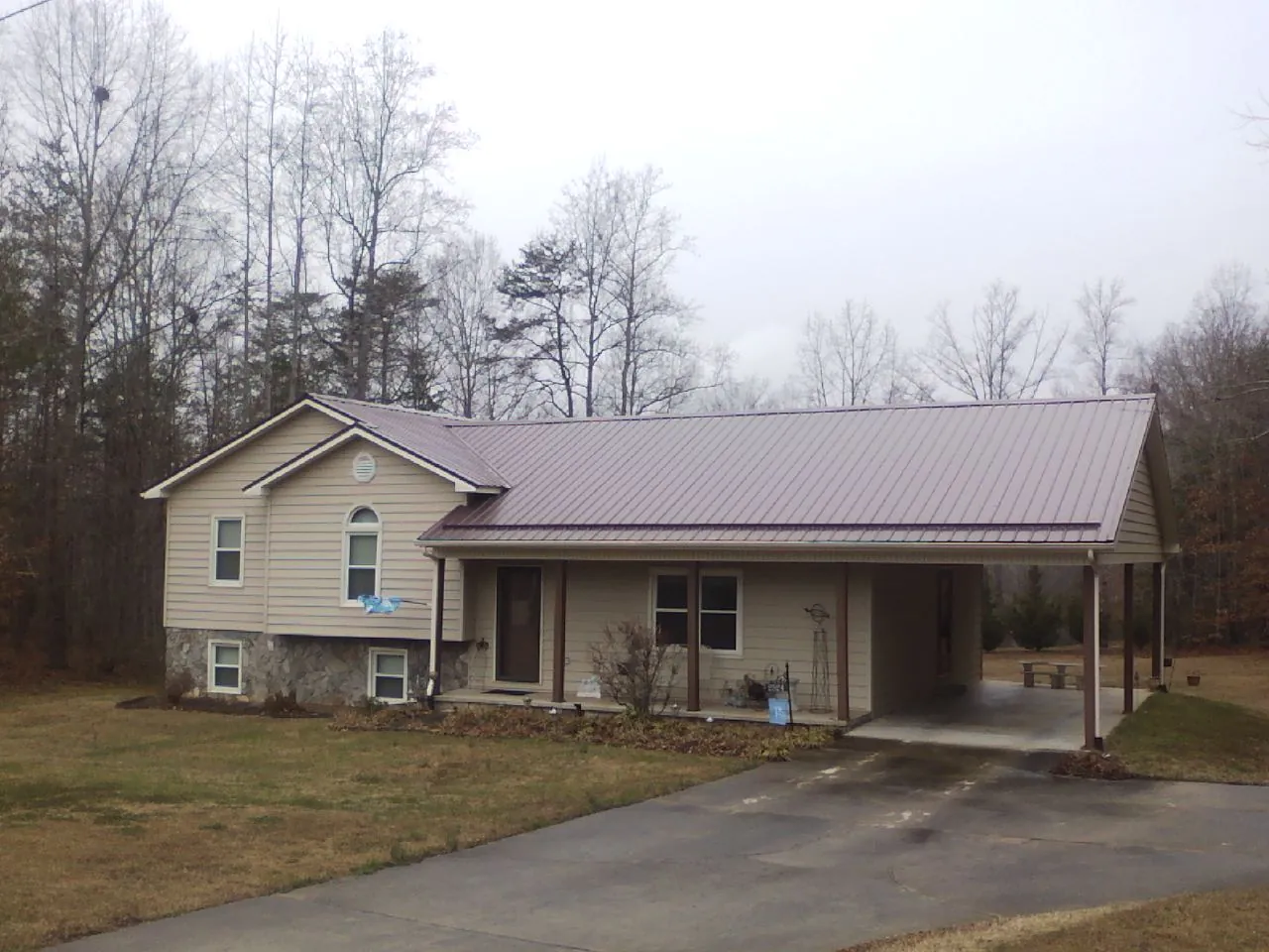 Burgundy metal roof on a tan split level home with an attached carport in Linden