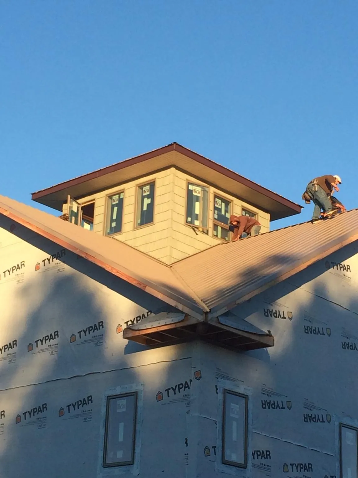 Roofers working around a rooftop cupola on a new metal roof at sunset — Roof Waterproofing in Linden by Roofing Brothers